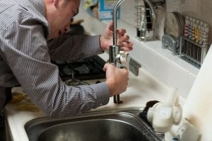 plumber investigating a tap and sink